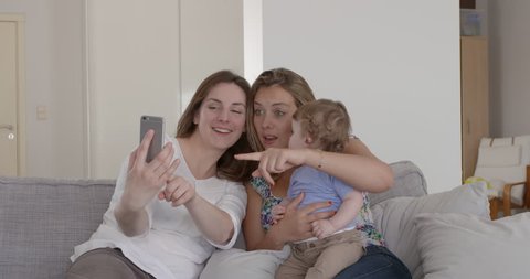 two friends or couple taking a selfie with 1 year old baby Stock Video