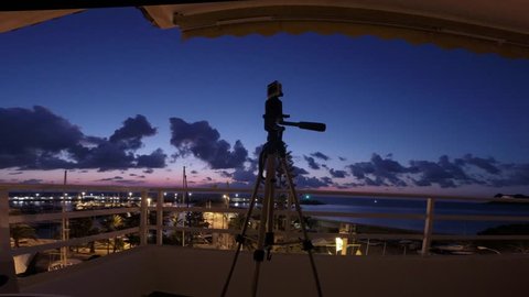 Small Camera on tripod taking shot time lapse during sunrise with marina, yachts and sea in the background. Image setting - Altea, Costa Blanca, Spain