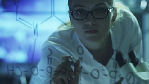 Woman Scientist is Drawing Organic Chemical Formulas on Glass. Shot on RED Cinema Camera in 4K (UHD).