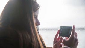 Person documenting travel with smartphone. Attractive woman traveling abroad and video recording everything around, transporting with ship on sea and shooting surroundings.