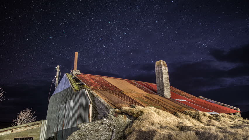 Abandoned house under starry sky and dark passing clouds time lapse 4k