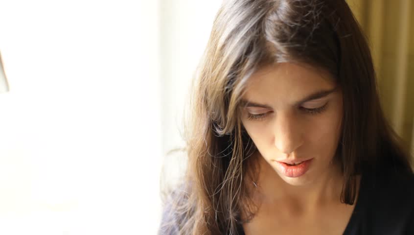 Young adult woman listening music on smartphone through earphones. Relaxed mood. Indoors. Natural lighting.