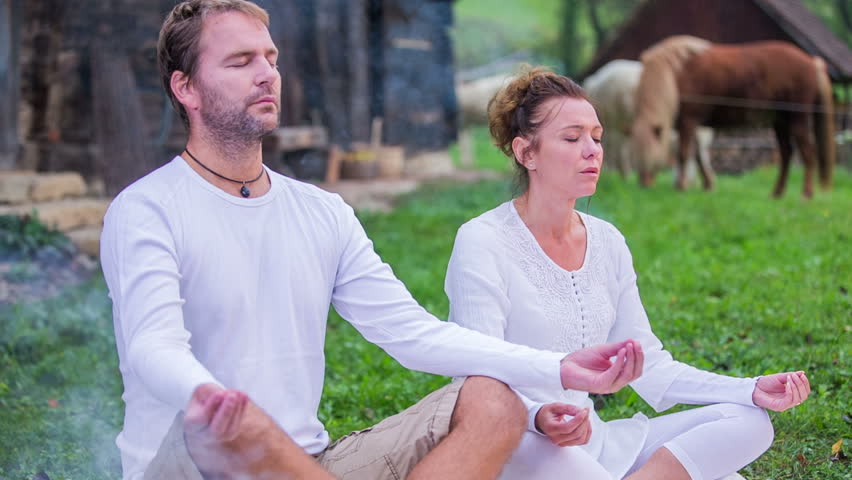 Couple looks in the sky . Slow motion RAW footage of a couple doing yoga and looking in the sky in the grass on the countryside on the sunny day.