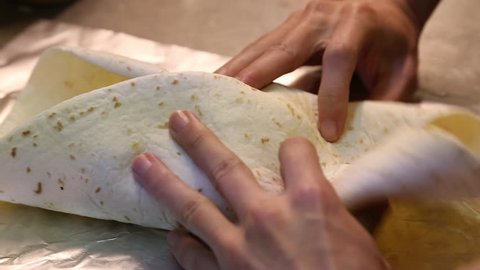 An Asian man preparing Mexican food, making delicious burritos in the kitchen of a Mexican restaurant-Dan