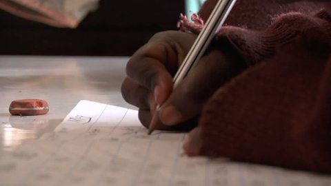 Close shot of a child writing and erasing on loose-leaf paper. Shot in Kenya in high definition.