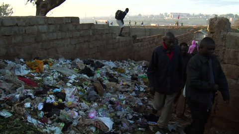 NAIROBI, KENYA - CIRCA JULY 2009: Kenyans walk near piles of trash. Shot in high definition.