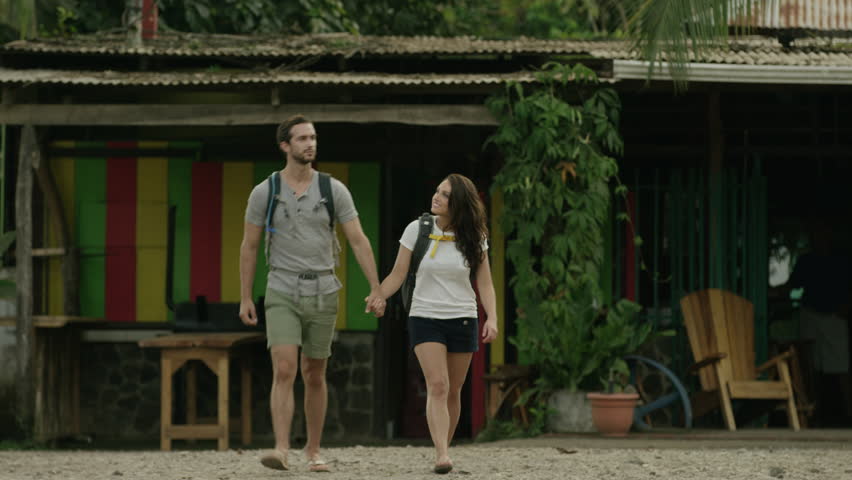 Medium panning shot of couple walking in village: Esterillos, Puntarenas, Costa Rica