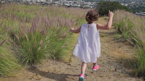 Happy girl in white dress running away towards Los Angeles cityscape on trail in Hollywood Hills, California. Vídeo Stock