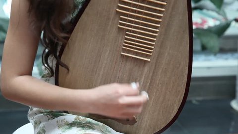 Chinese girl wearing  cheongsam playing the national instrument - Pipa.Pipa is a traditional four-stringed Chinese musical instrument,which has a pear-shaped wooden body.