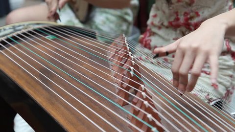 Chinese girl wearing a cheongsam playing the national instrument - Guzheng