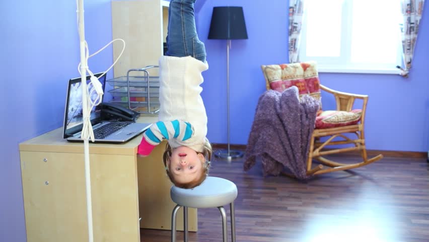 Little girl in jeans gets under table in inverted house