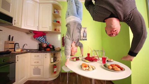 Parents and daughter upside down have fun in kitchen of inverted house