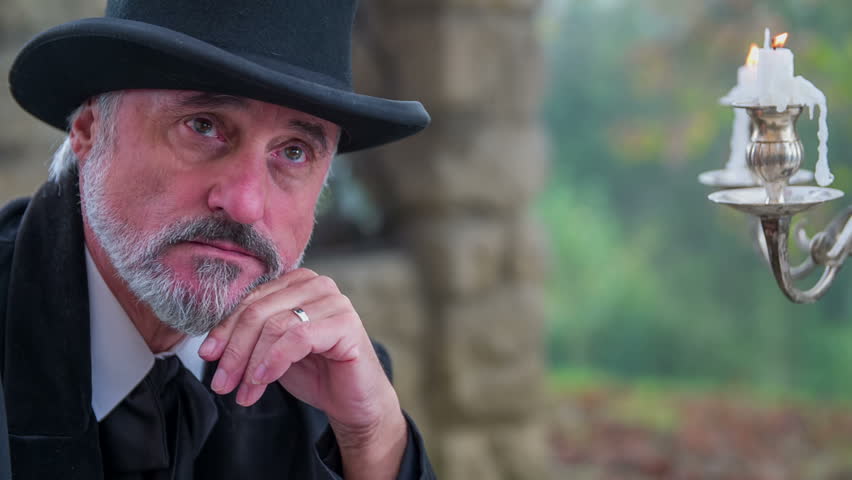 Writing a poem in beautiful scene with romantic composer. Close up zooming-in RAW footage of a man from modern time seating at garden table and writing a classic song.