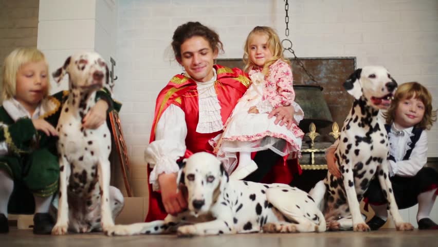Father in medieval costume with three children and three dalmatians near chimney