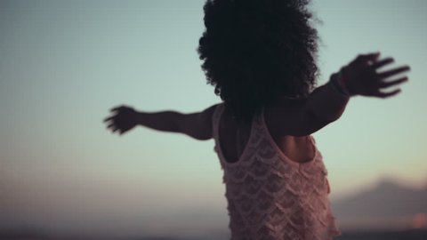 African american girl with afro haircut standing with arms wide spread enjoying the sunset