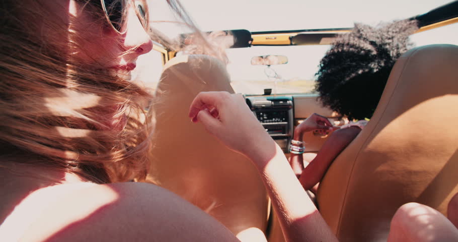 mixed racial group of carefree girl friends in a vehicle on a road trip together in Slow Motion