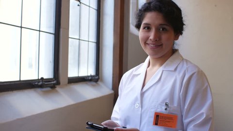 Hispanic female doctor looking into camera with tablet