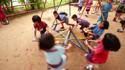 NAKHON RATCHASIMA, THAILAND - March 15: Kindergarten students in regional costume playing carousel in the playground. NAKHON RATCHASIMA, THAILAND - March 15, 2015