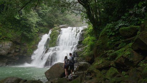 Wide slow motion zoom in of couple admiring waterfall in rain forest: Santa Juana, , Costa Rica