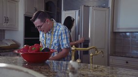 Happy couple cooking together while talking laughing, and goofing off, slow motion, 4k stock video clip. Dolly motion,