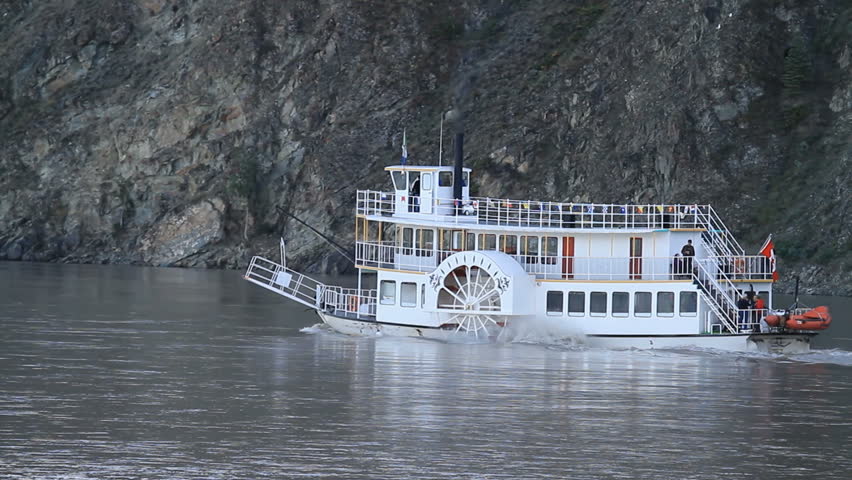 Boat with side paddles on Yukon River, Klondike gold area by Dawson City, Canada. Steaming upstream against current. Powerful ship for tourists, passengers and cargo.