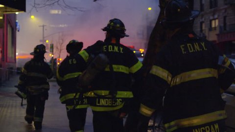 NEW YORK - MARCH 26, 2015: FDNY firefighters walking toward fire and smoke, silhouetted, slow motion in 4k, Manhattan NYC. FDNY responded to disaster; building collapse and fires in East Village.