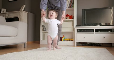 One year old baby having fun learning to walk