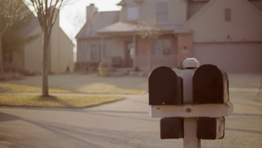 Man and woman collect letters from mailbox in a typical suburb of the USA