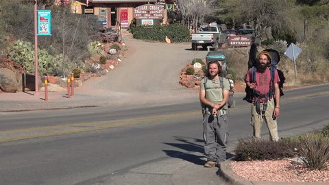 SEDONA, ARIZONA - JAN 2015: Sedona Arizona downtown men hitchhikers leaving town. Tourist section road traffic. Red sandstone formations. Destination for natural, spirituality and organic lifestyle.