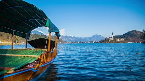 Tourist boat parked out of season. Static shot of beautiful tranquil view of lake Bled clear blue water, church in background. Sunny day.