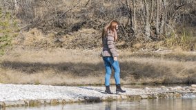 Person puts hand in cold lake water. Female person touches cold water in pond. Sunny day.