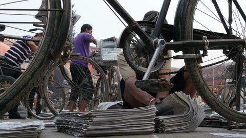 AMRITSAR, INDIA - 3 OCTOBER 2014: Men organize newspapers at a sorting station, before delivery by bicycle, in Amritsar.