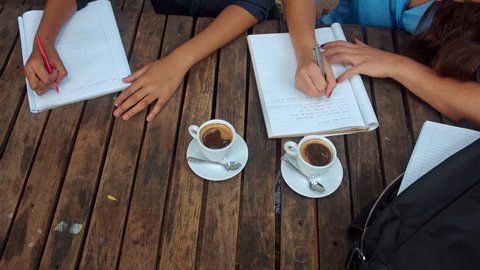 Above angle view of casual entrepreneur woman team/student team, writing down the brainstorming session, wile in a coffee meeting at cafe.