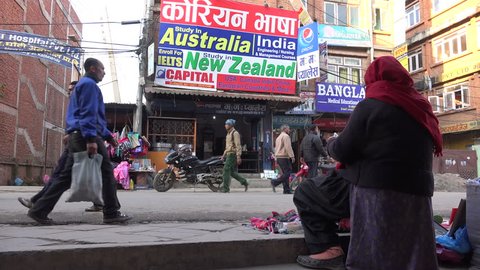 KATHMANDU, NEPAL - 4 JANUARY 2015: People walk past billboards advertising to study abroad, a popular activity by many students in Nepal and other countries, in Kathmandu.
