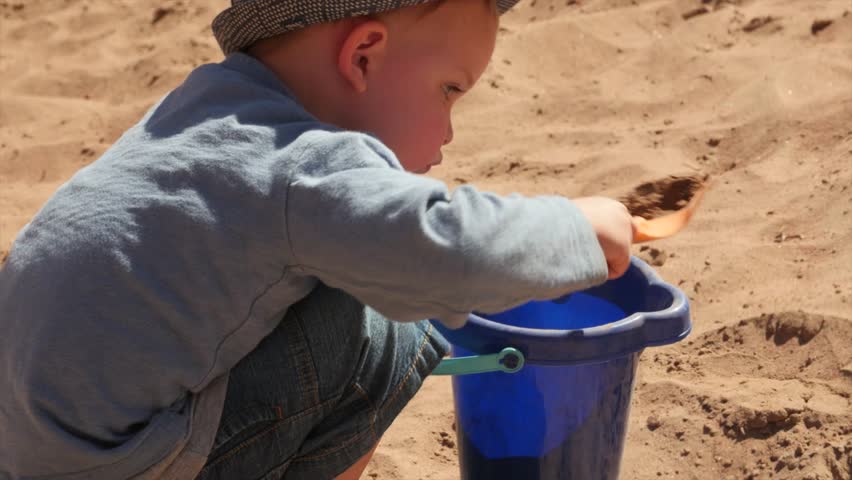 A little boy playing on a sandy beach and walking in the water of the Colorado River near Moab in Southern Utah