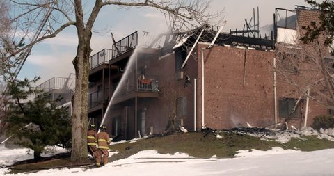 Firefighters spraying water on apartment building fire in winter