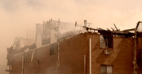 Smoldering apartment building fire with smoke and charred wood aftermath