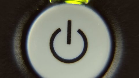 A power button being turned on and off by a human finger. A green blinking LED is above the symbol. Macro detail shot.
