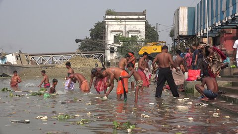 KOLKATA, INDIA - 8 DECEMBER 2014: Men take a bath at a classic bathing ghat in the Hooghly river in Kolkata.