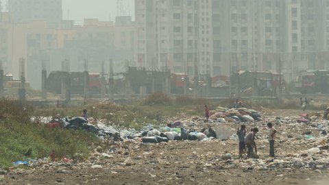 MUMBAI, INDIA - 9 NOVEMBER 2014: Unidentified people work at the Deonar garbage dump, as garbage trucks drive on and off, in Mumbai. 