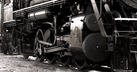 Heavy industrial steam locomotive train engine wheels passing in slow motion.