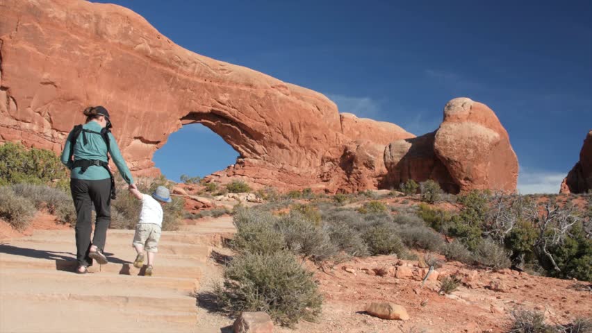 A young mother and her kids walking by North Window and Turret arch in Arches National Park in Southern Utah near Moab