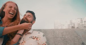 Slow motion video of a laughing girl making a new moustache for her hipster boyfriend with her hair as a joke