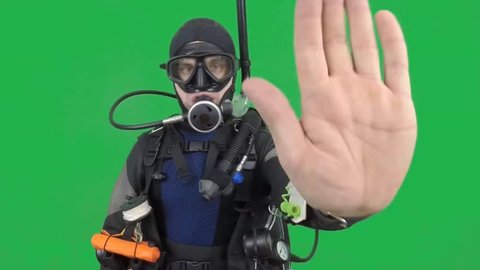 Dive instructor shows sing: STOP  also a available on the green screen all of diving sings from course  with full dive gear (open water diver)