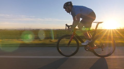 healthy man riding bicycle working out fitness outdoors at the sunset.  tracking shot 4k from camera car