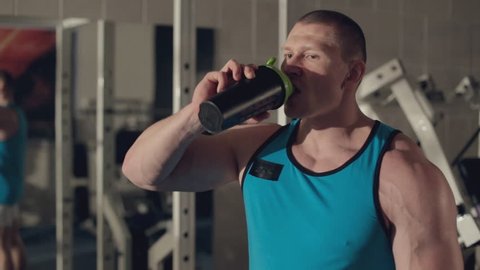 Muscular man drinking water after grueling workout