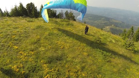 Paraglider takes off over the woods and goes away into the wildernes