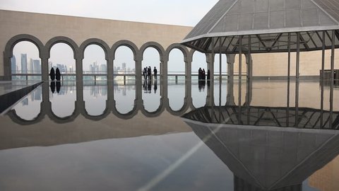 DOHA, QATAR - 18 JANUARY 2015: Reflection of people visiting the Museum of Islamic Art, with arches and the Doha skyline in the background.