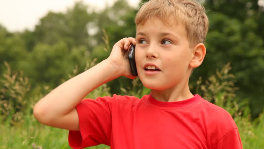 Boy is speaking on his mobile phone in the park on a sunny summer day. | Shutterstock HD Video #953167