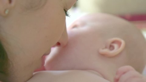 Mother kissing and hugging her newborn Baby. Beautiful mom with her little child portrait. Happy Family together. Parenthood, motherhood concept. Slow motion 240 fps. Full HD 1080 Stockvideo